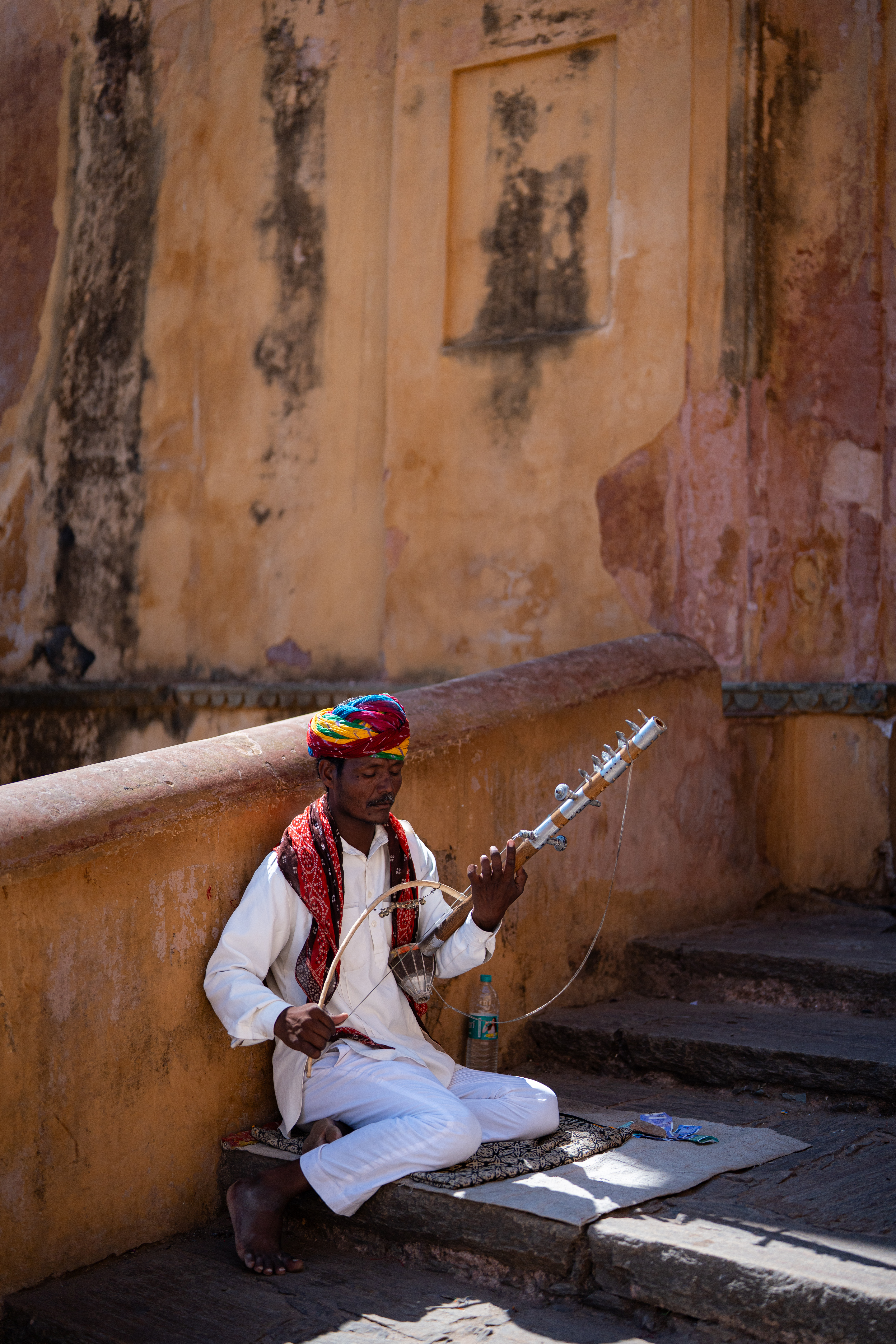 Musician in a colorful turban playing a traditional string instrument